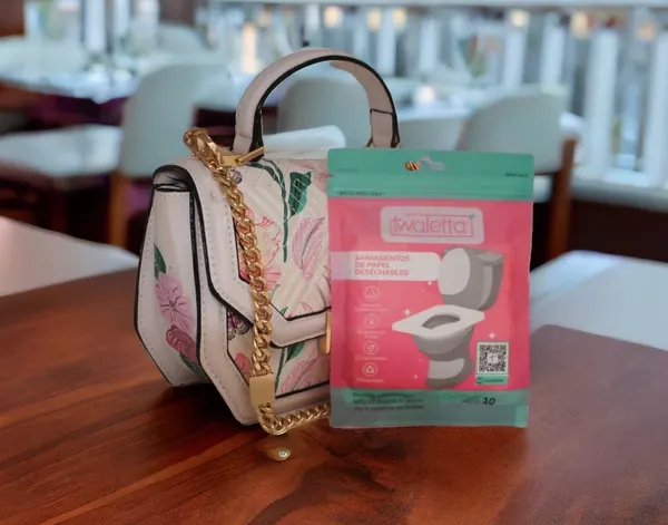 Sobre de saniasientos Twaletta junto a un bolso en un restaurante